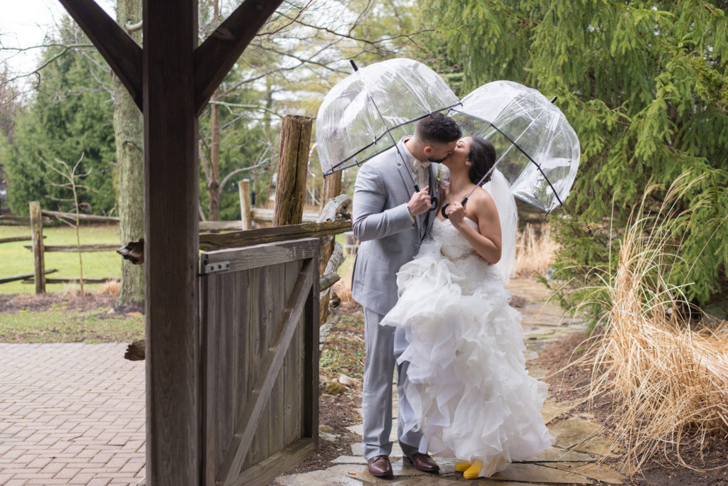 a bride and groom pose with umbrellas in the rain at bellamere winery