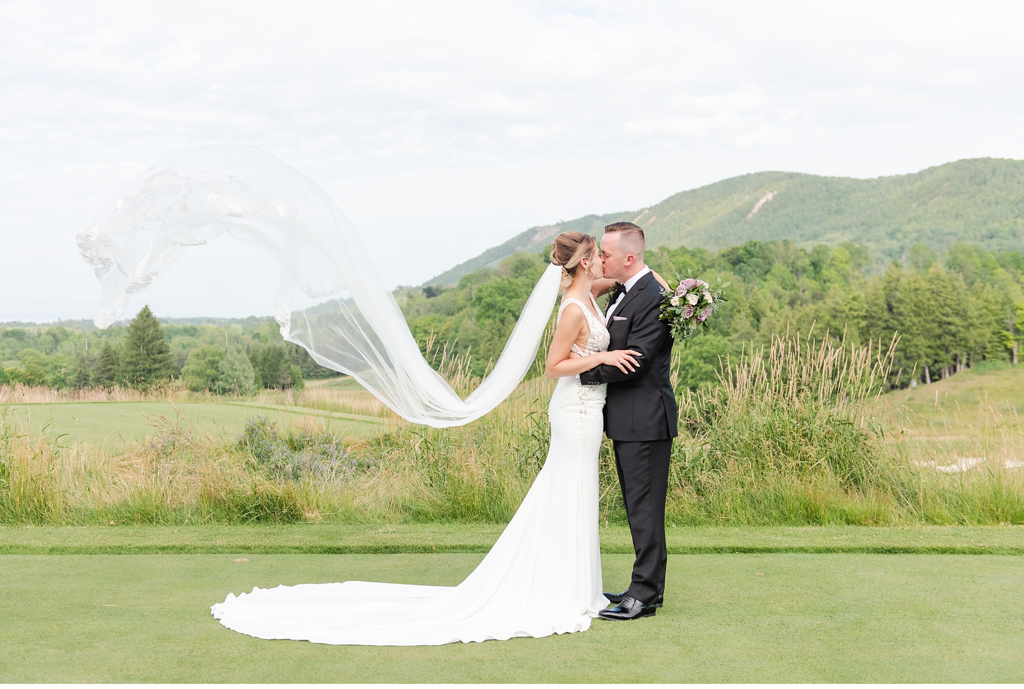 a brides veil blows in the air as she kisses the groom at their blue mountain wedding