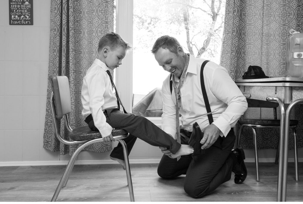 a groom puts his sons shoes on to get ready for his Grand Bend wedding