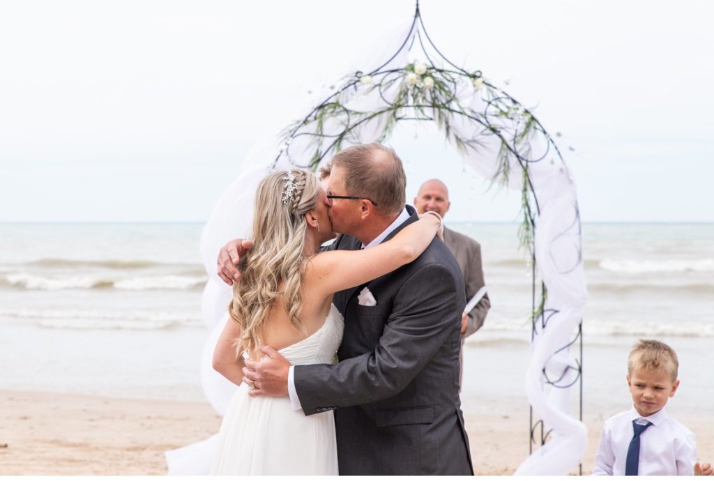 a father kisses his daughter on the cheek as he gives her away at her Grand Bend wedding