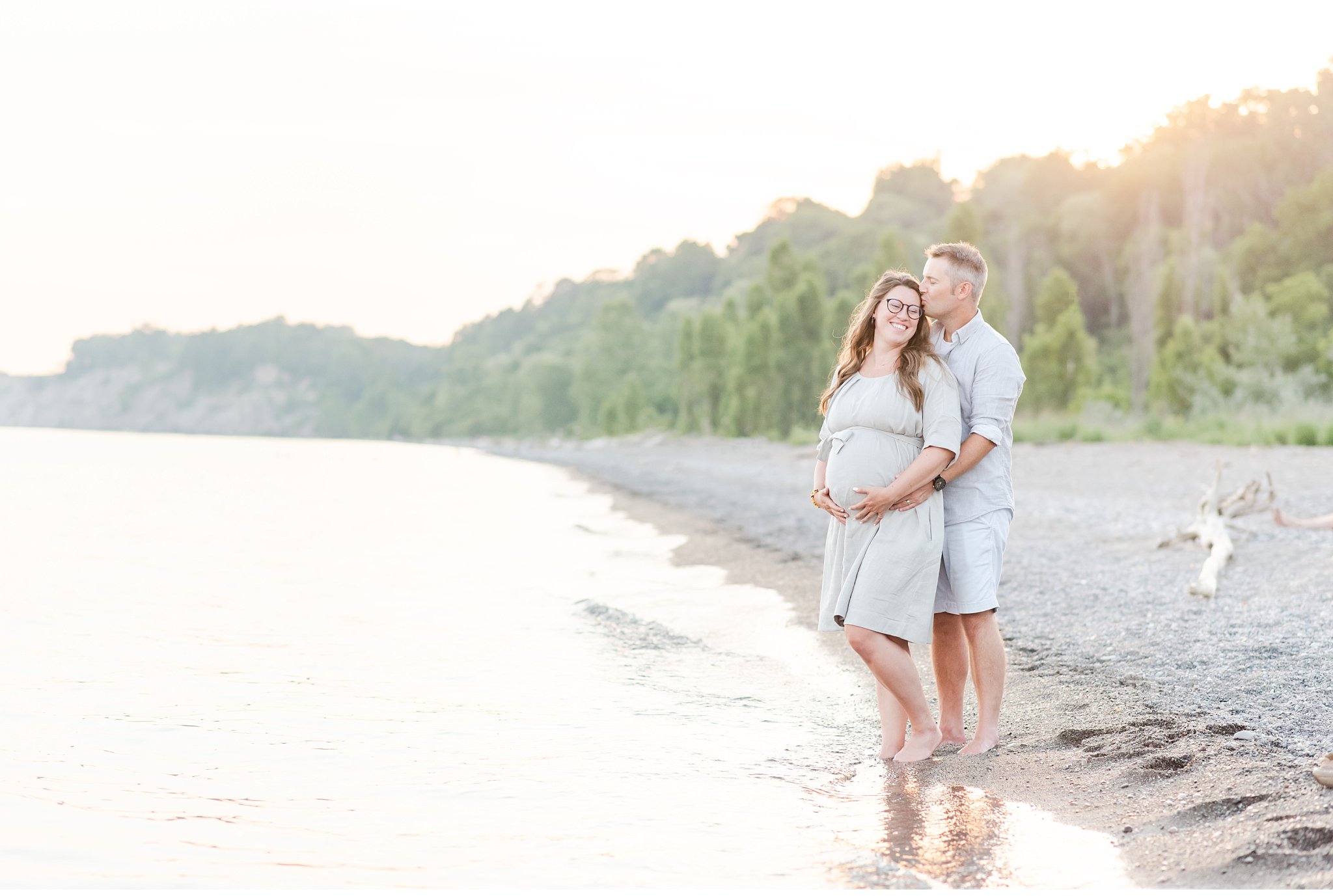 a couple having maternity photos taken on the beach at sunset in port stanley ontario