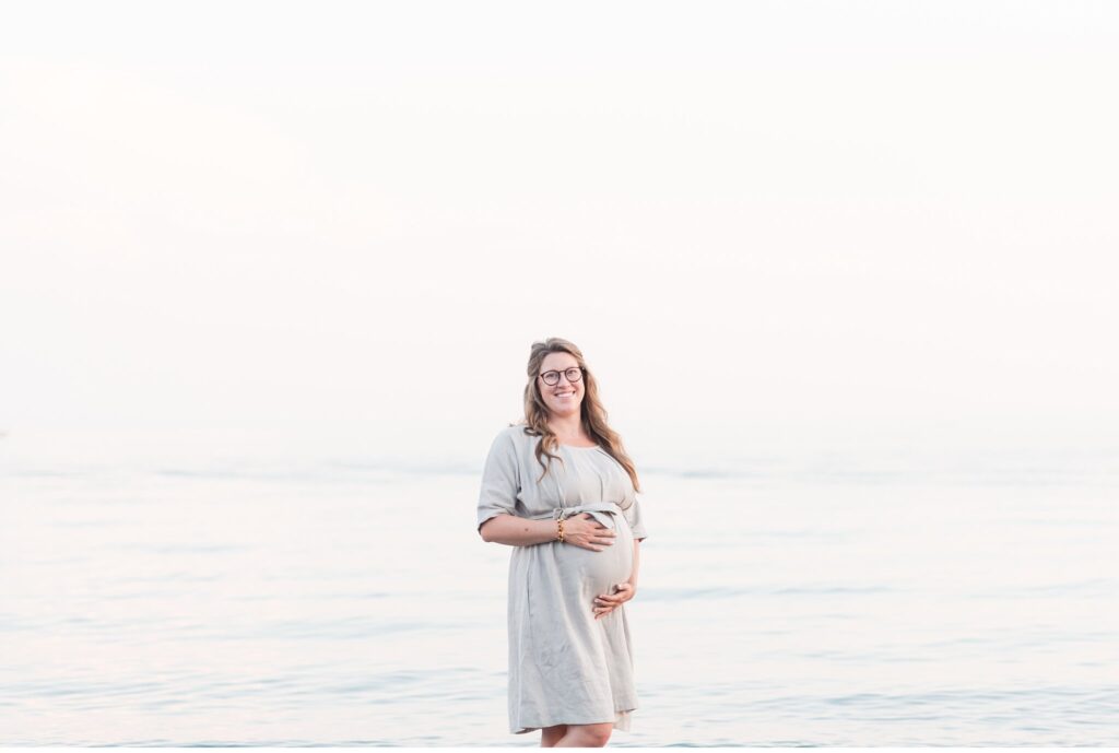 a mom-to-be posing for maternity photos by lake erie in port stanley ontario