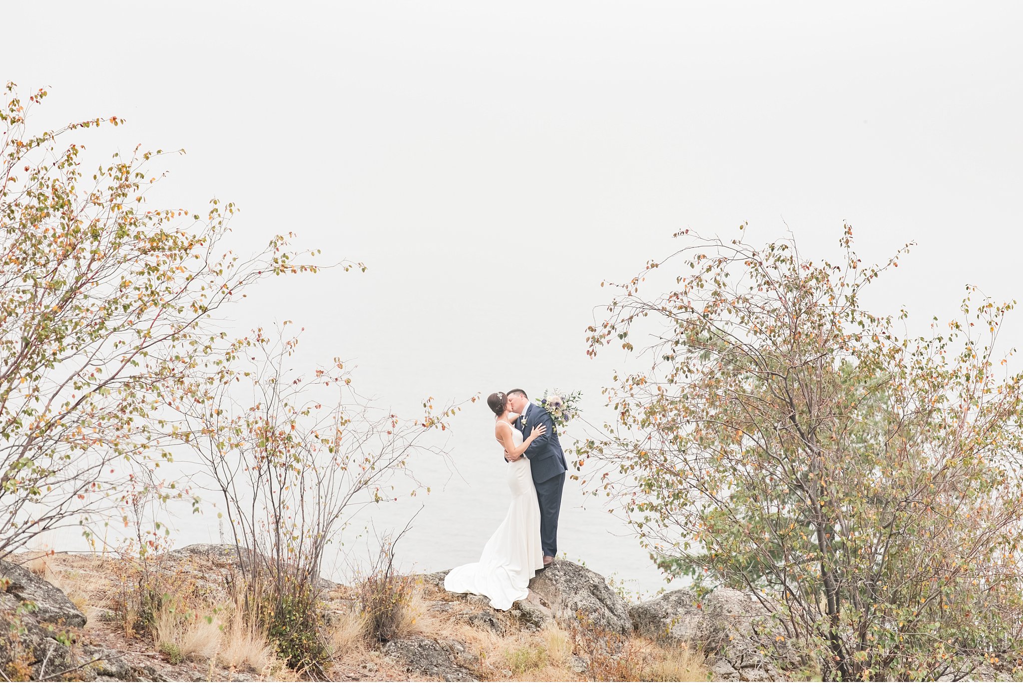 bride and groom pose together on a mountain in kelowna, british columbia