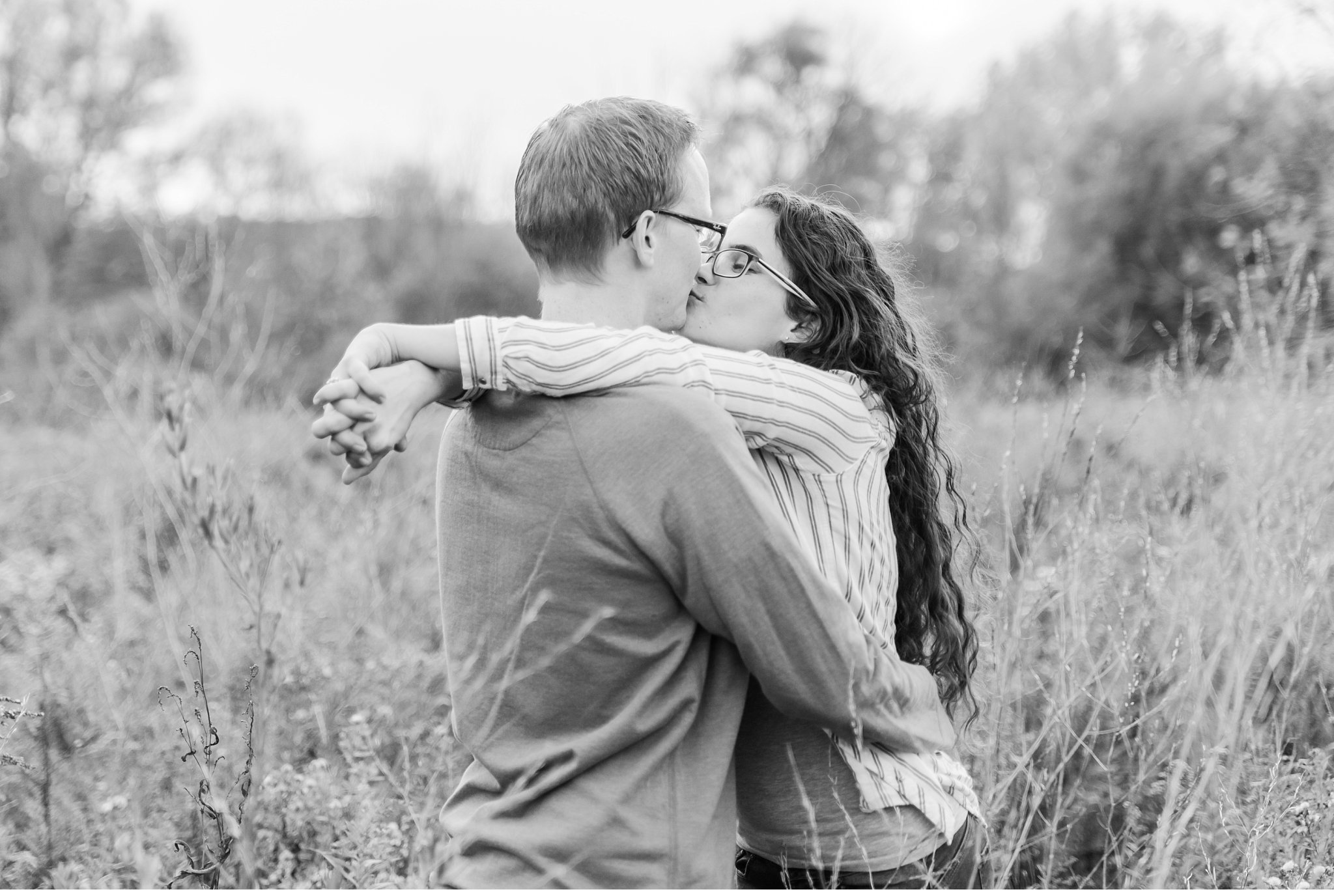 A couple kissing in a field during their engagement session