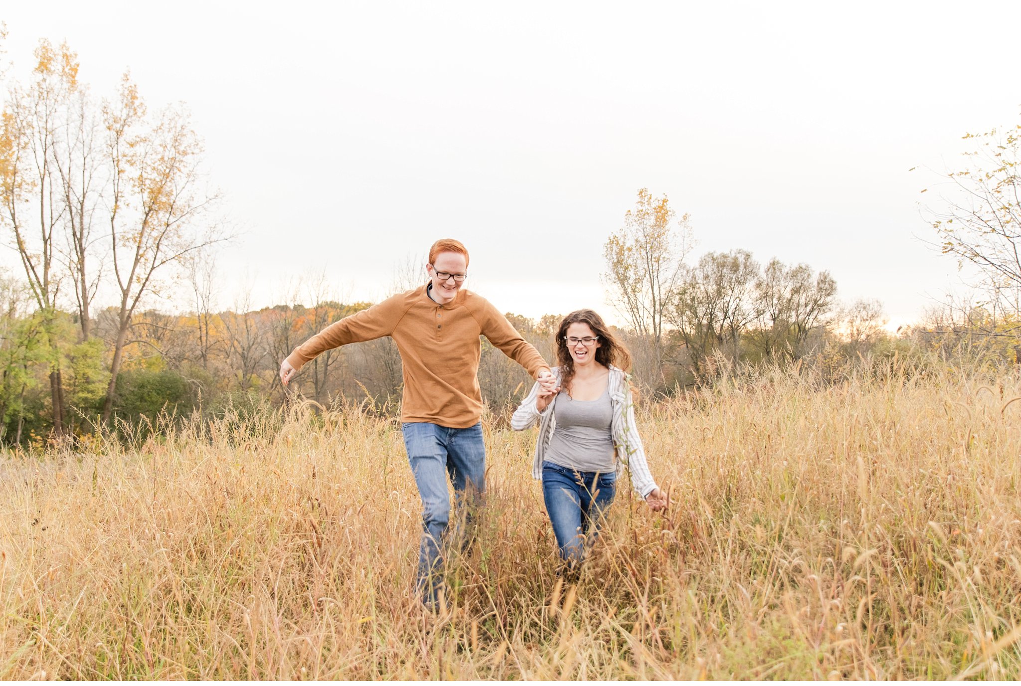 A couple running through a field together during their engagement session