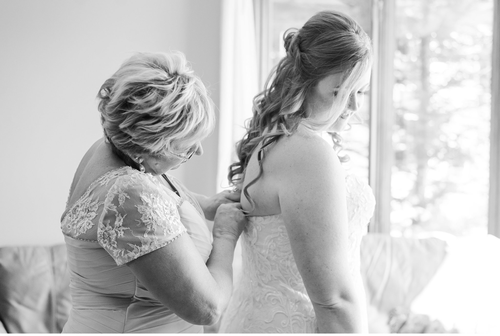 bride's mom doing up the back of her wedding dress