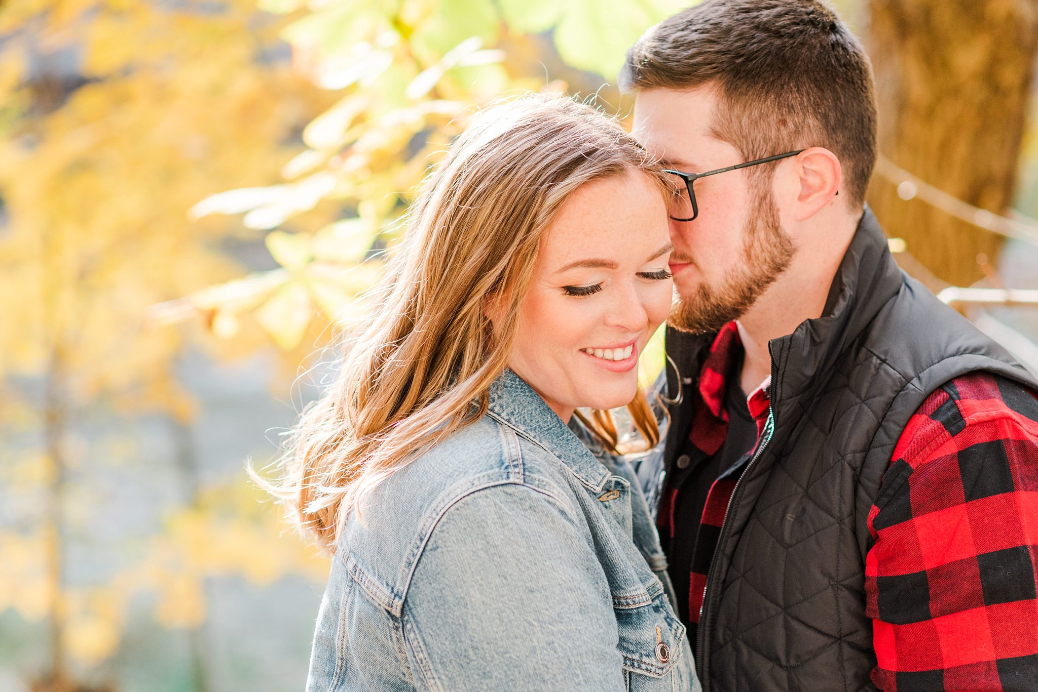 an engaged couple with fall leaves during their engagement session