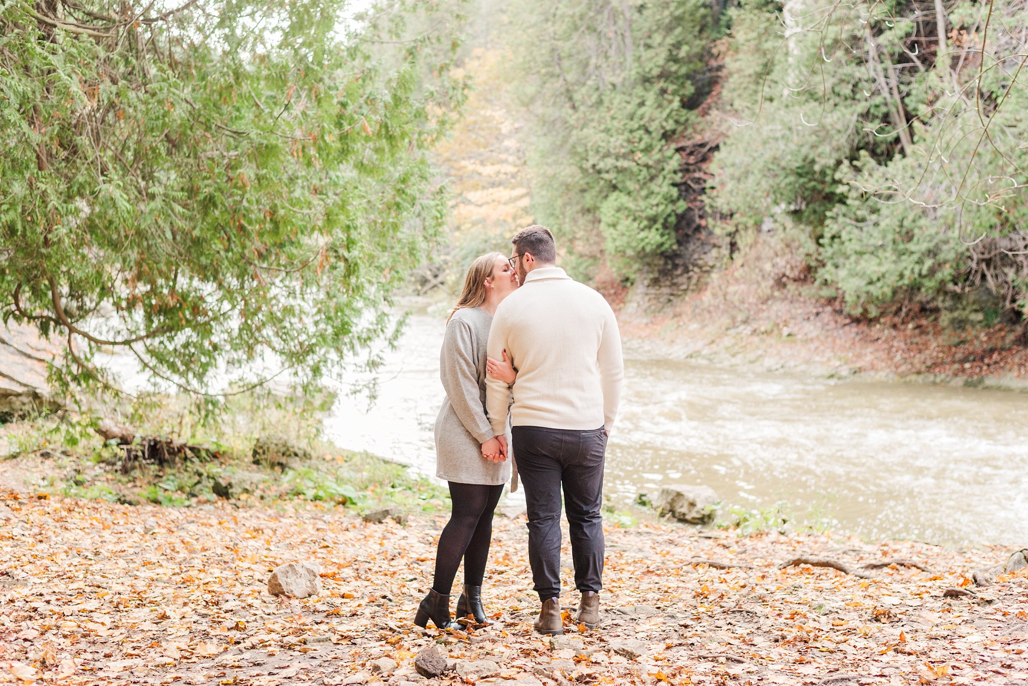 an engaged couple kisses along the river during their engagement session