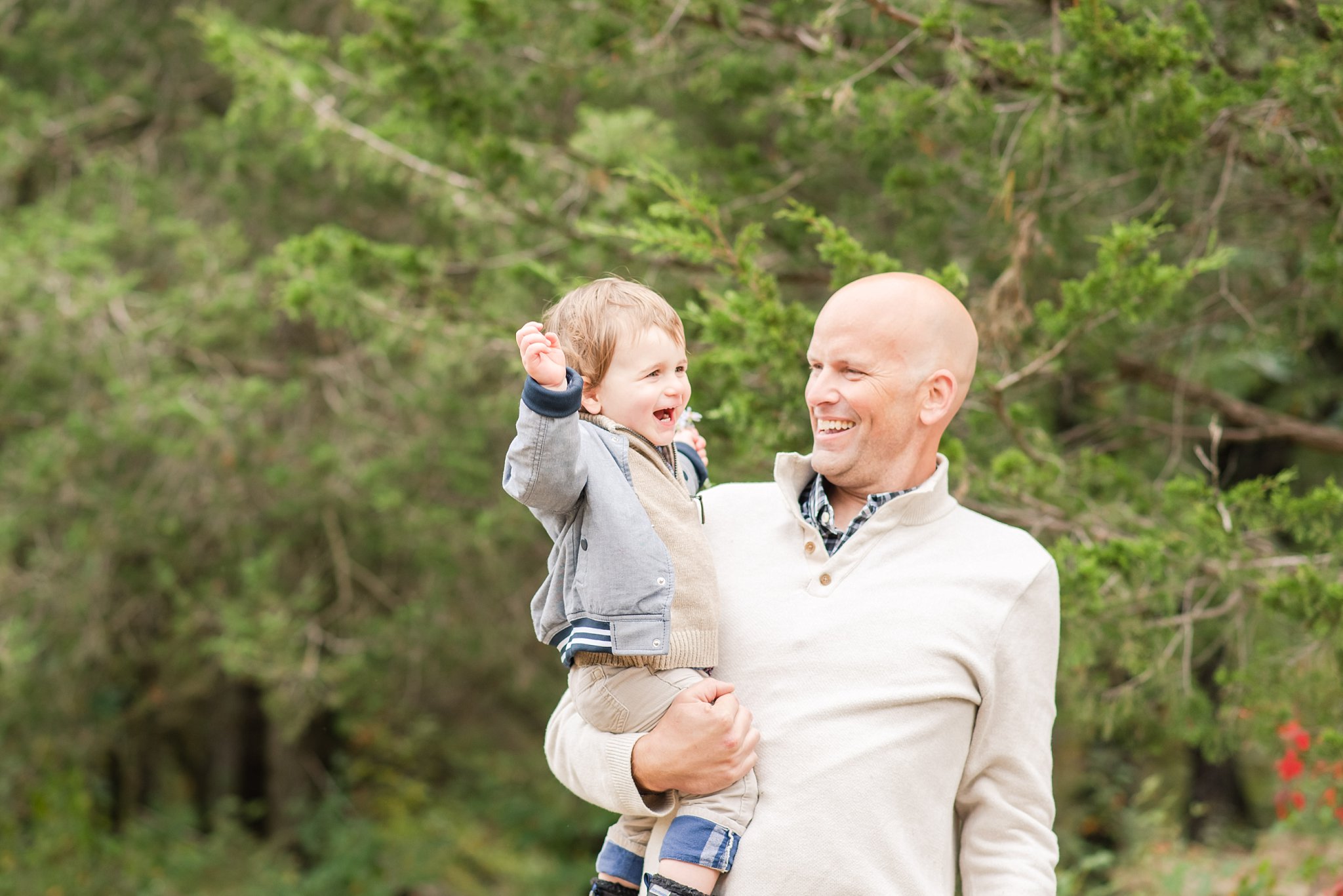 family photos in fall; dad holds his son who is throwing his arms up happily
