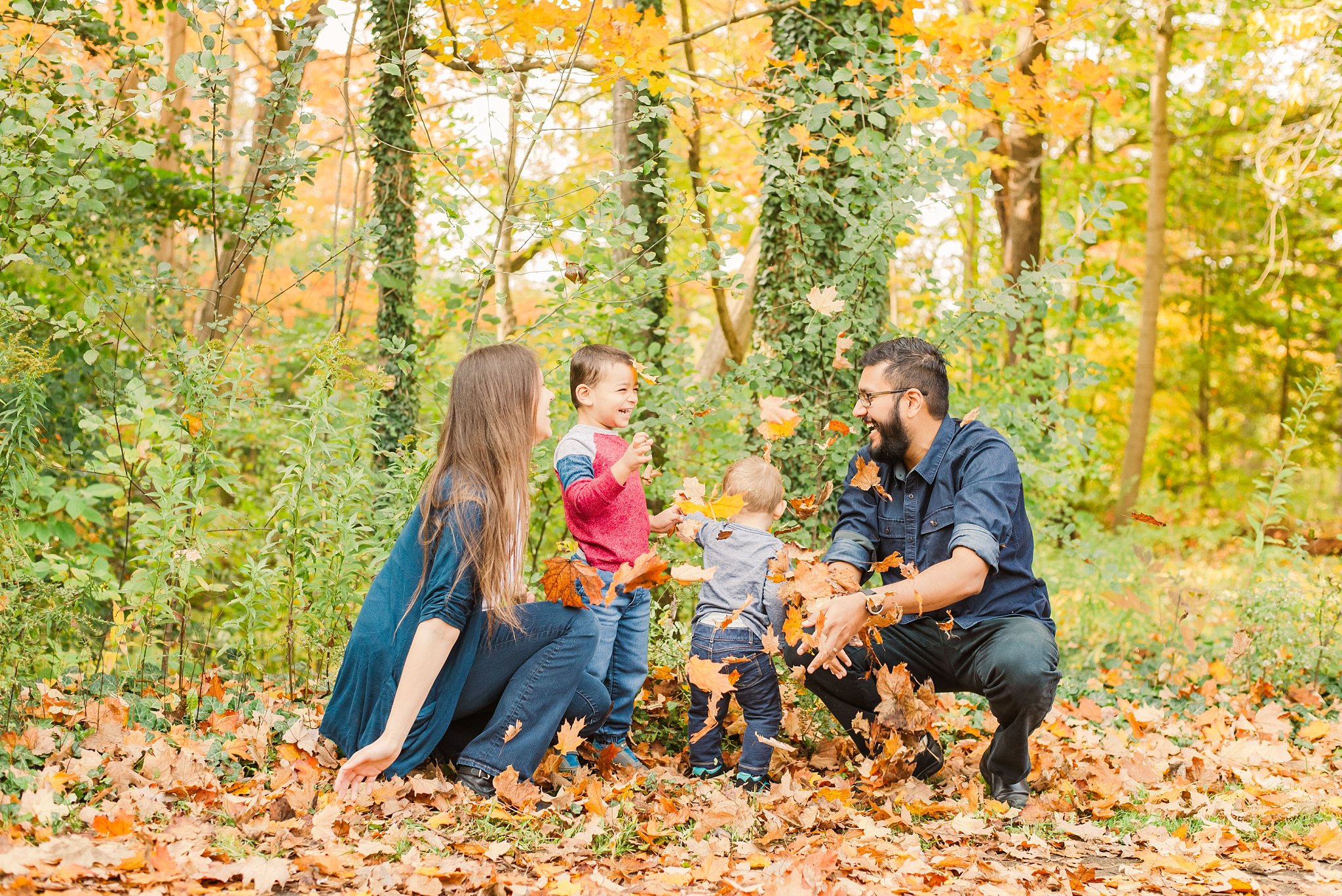 fall family photos in springbank park; parents throw leaves with their sons