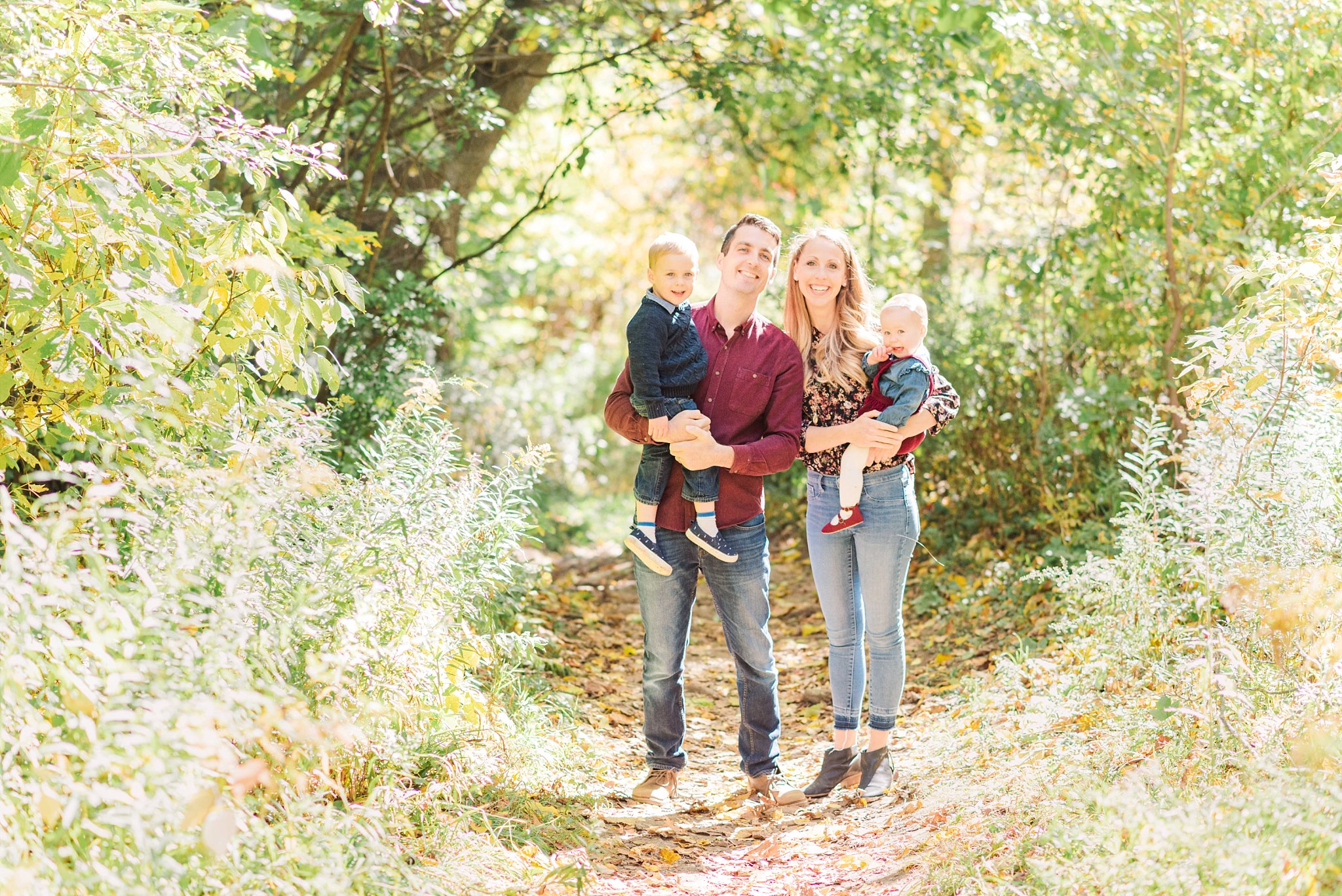 fall family photos in london ontario; family stands on a tree-lined path