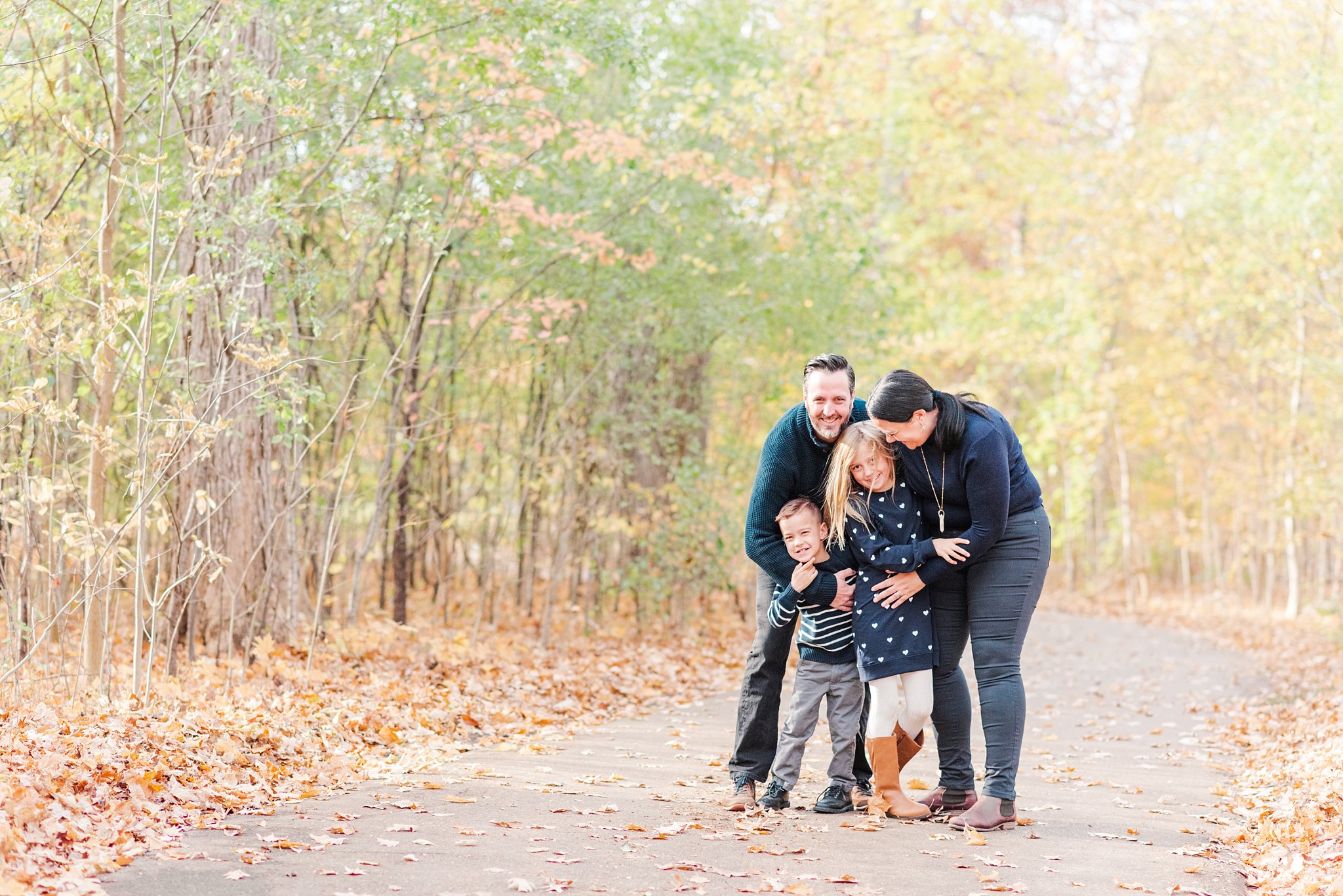 fall family photos in london ontario; family hugs and laughs on a tree-lined path