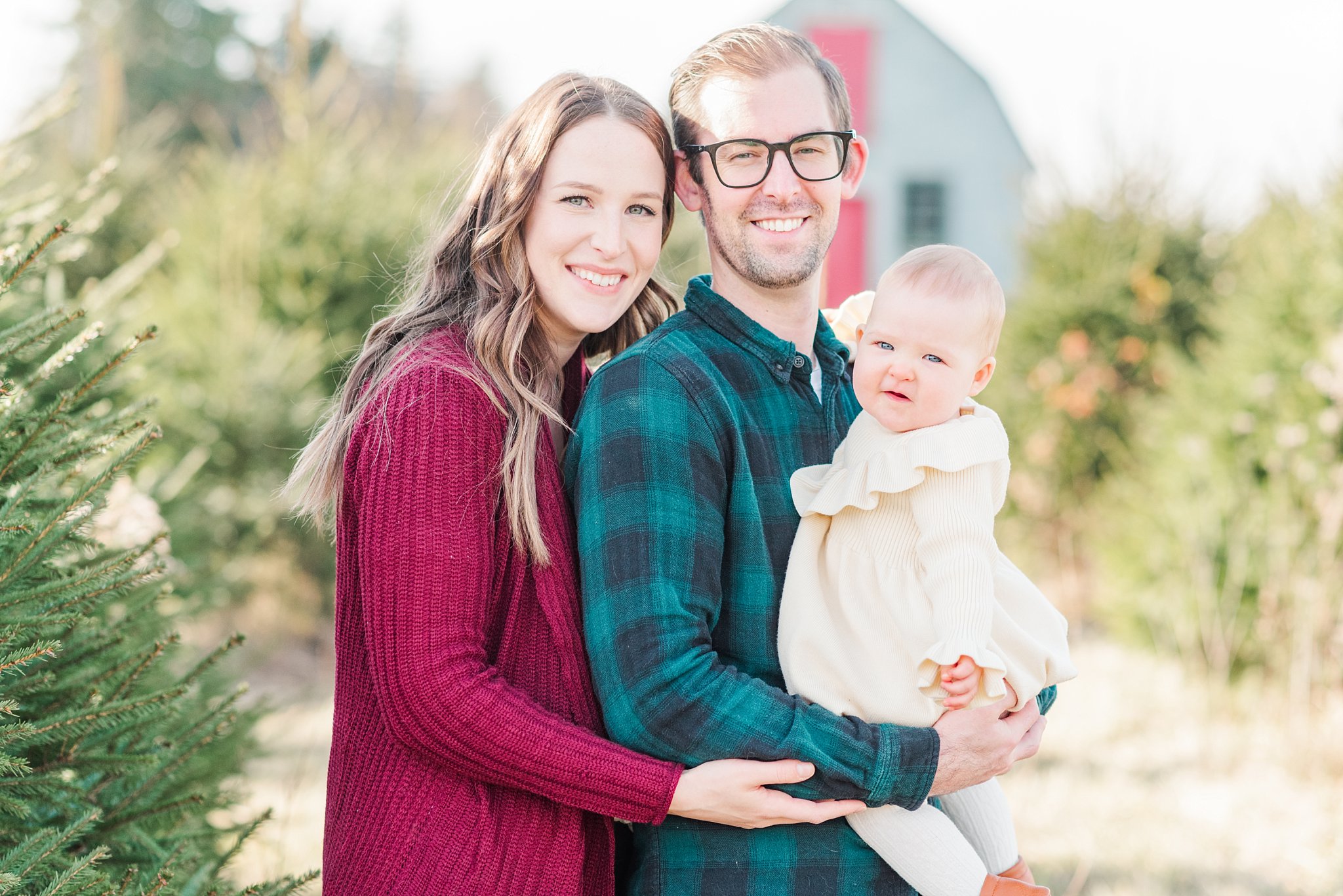 family photos in london ontario; parents with their daughter on a christmas tree farm