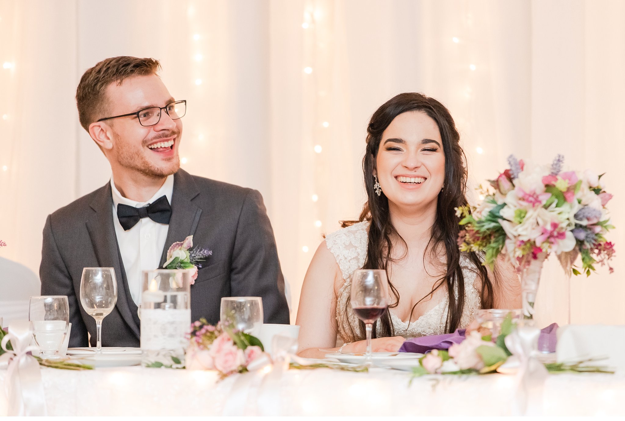 a groom and a bride laugh listening to someone give a speech during their london ontario wedding