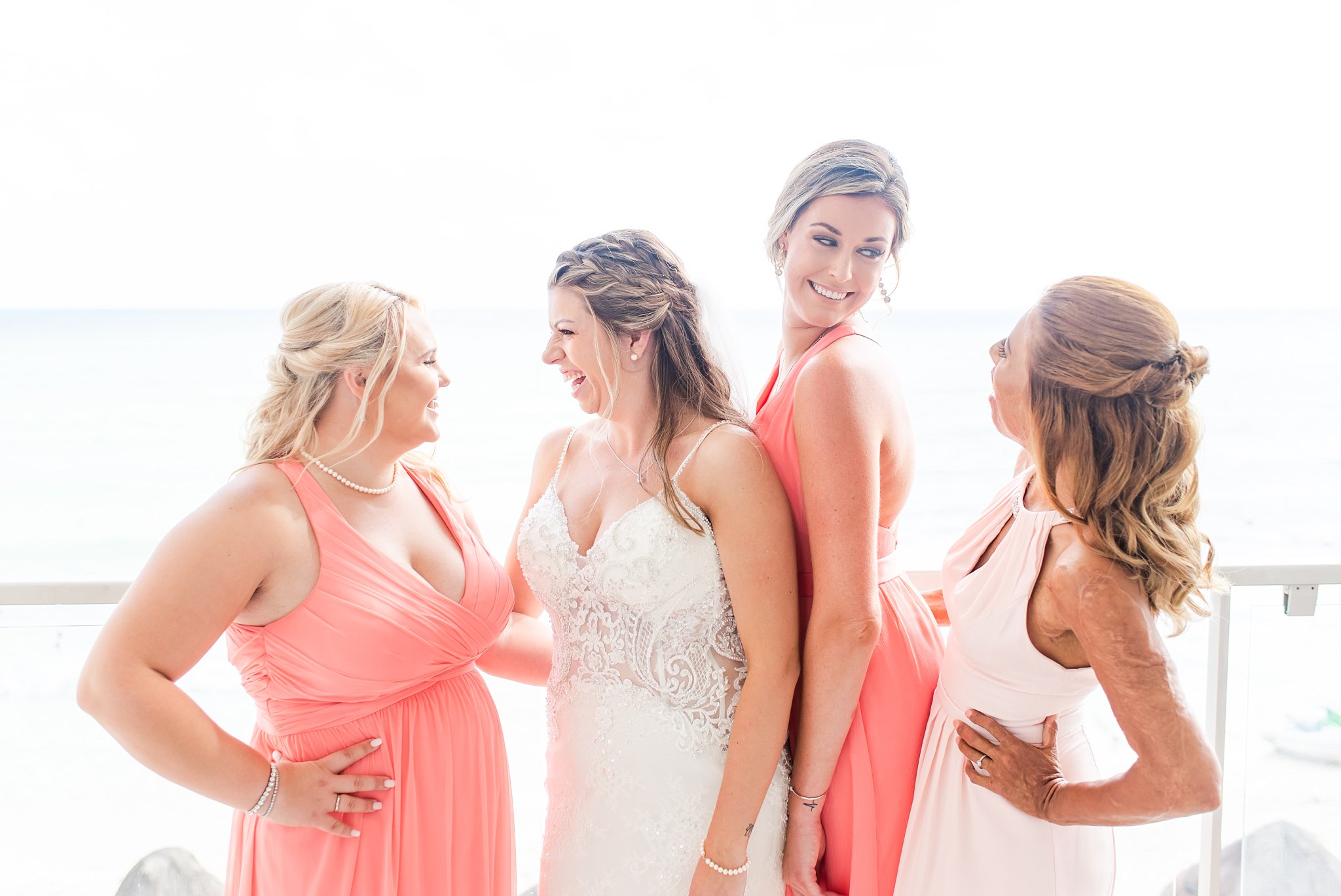 A bride and her bridesmaids stand on a balcony laughing with one another in Cancun Mexico at a destination wedding by Wedding Photographer in London Ontario Life is Beautiful Photography