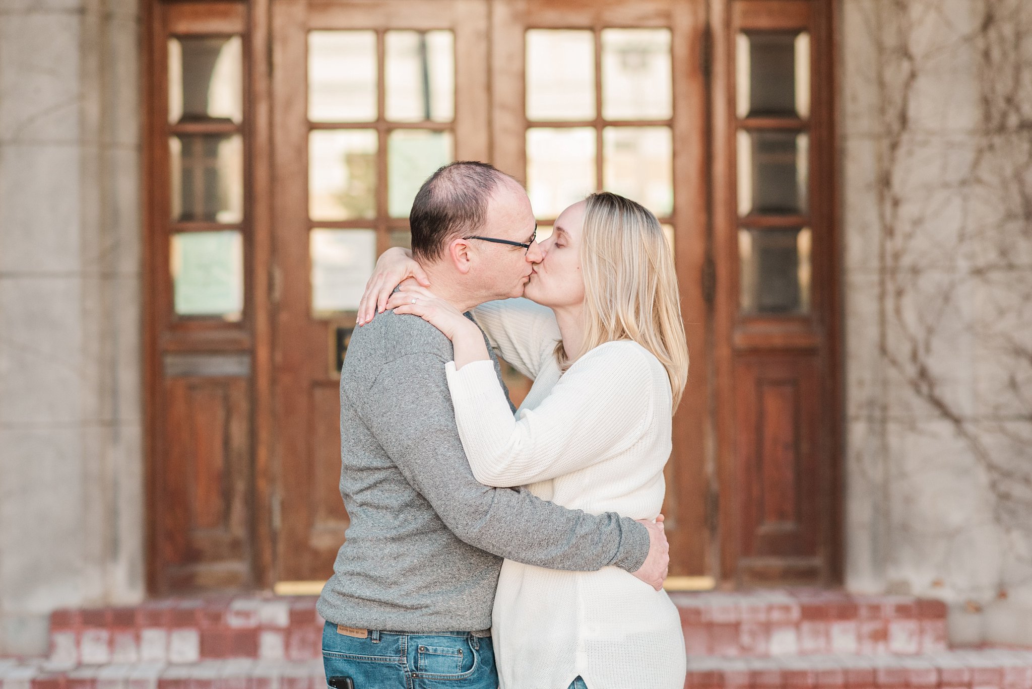 a couple kisses in front of the door at the old courthouse during their engagement session with wedding photographers in london ontario life is beautiful photography