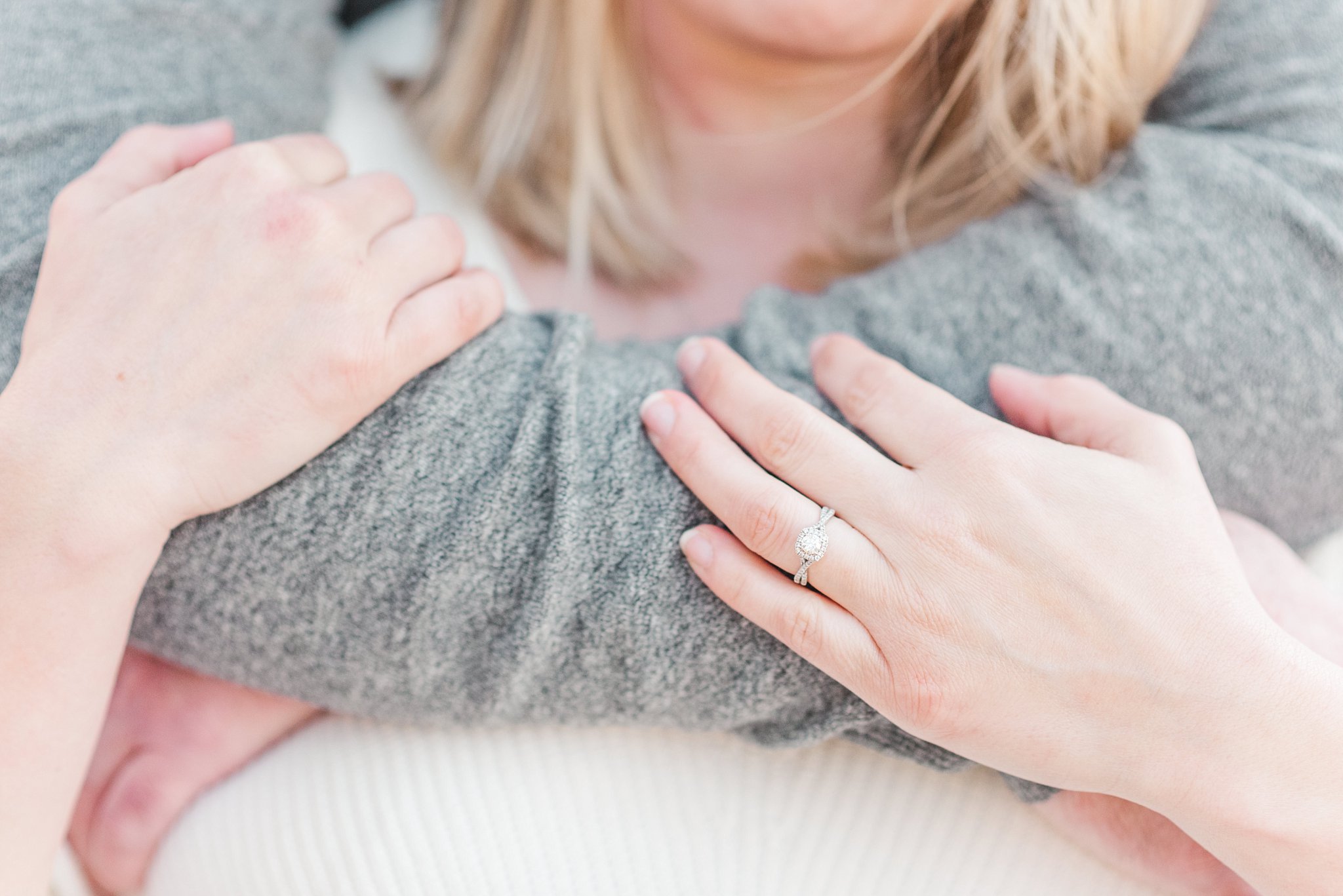 a close up of an engagement ring and a couple's arms during their engagement session