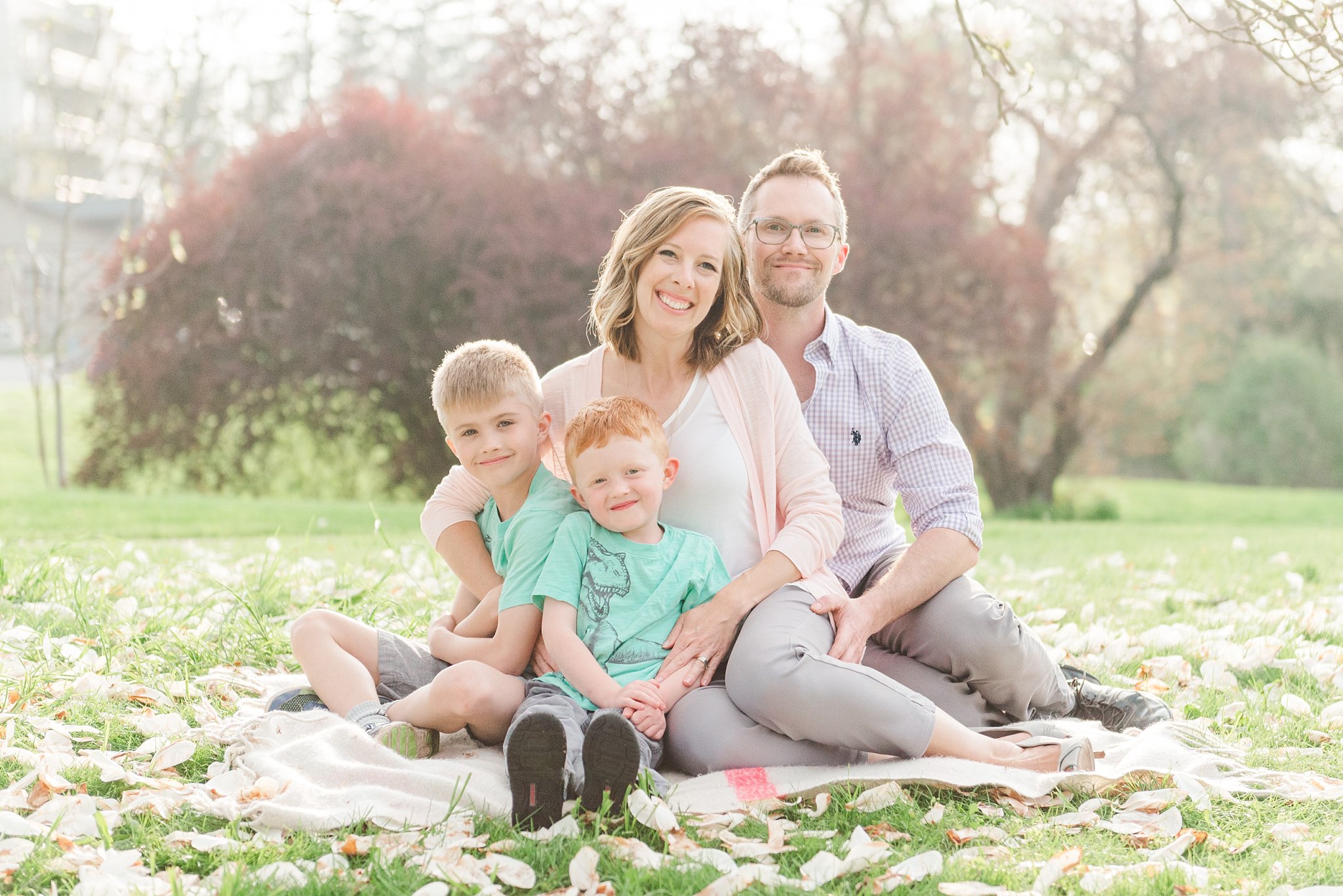 a family of four sits on a blanket and smiles during their spring mini session with london ontario family photographer life is beautiful photography