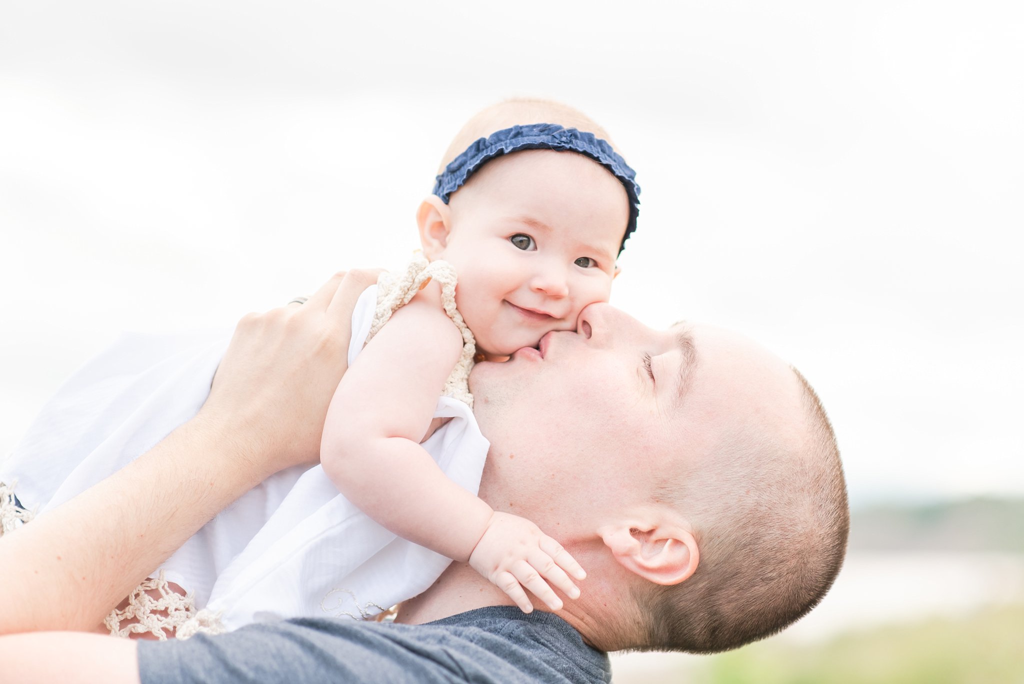 a father kisses his daughter on the cheek as he lifts her in the air. family photography london ontario. by life is beautiful photography
