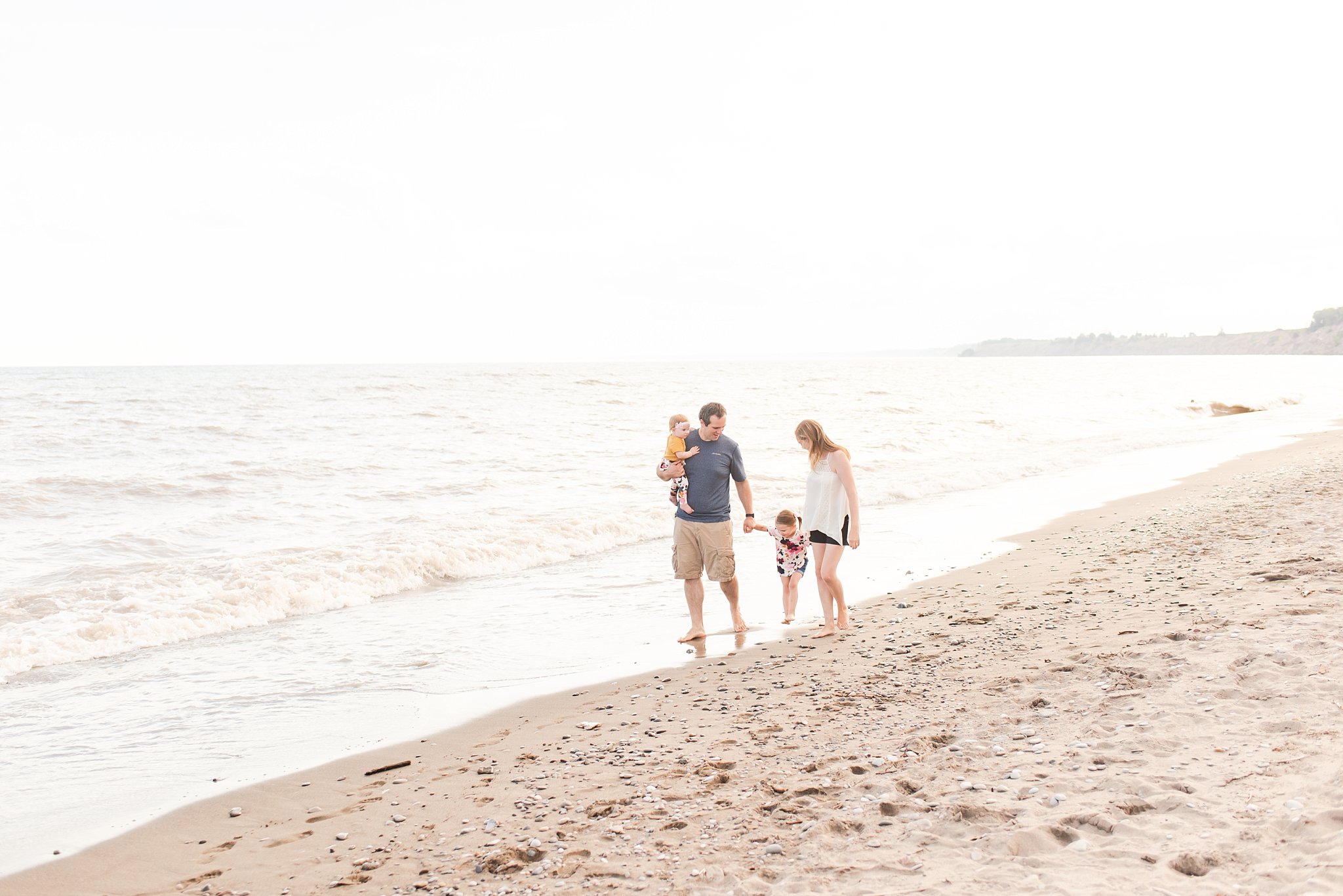a family of four walks down the beach in port stanley at sunset. family photography london ontario