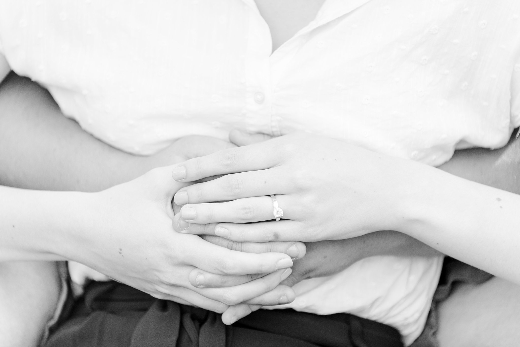a black and white photo of a couple's hands, overlapping one another, displaying an engagement ring. wedding photographers in london ontario.