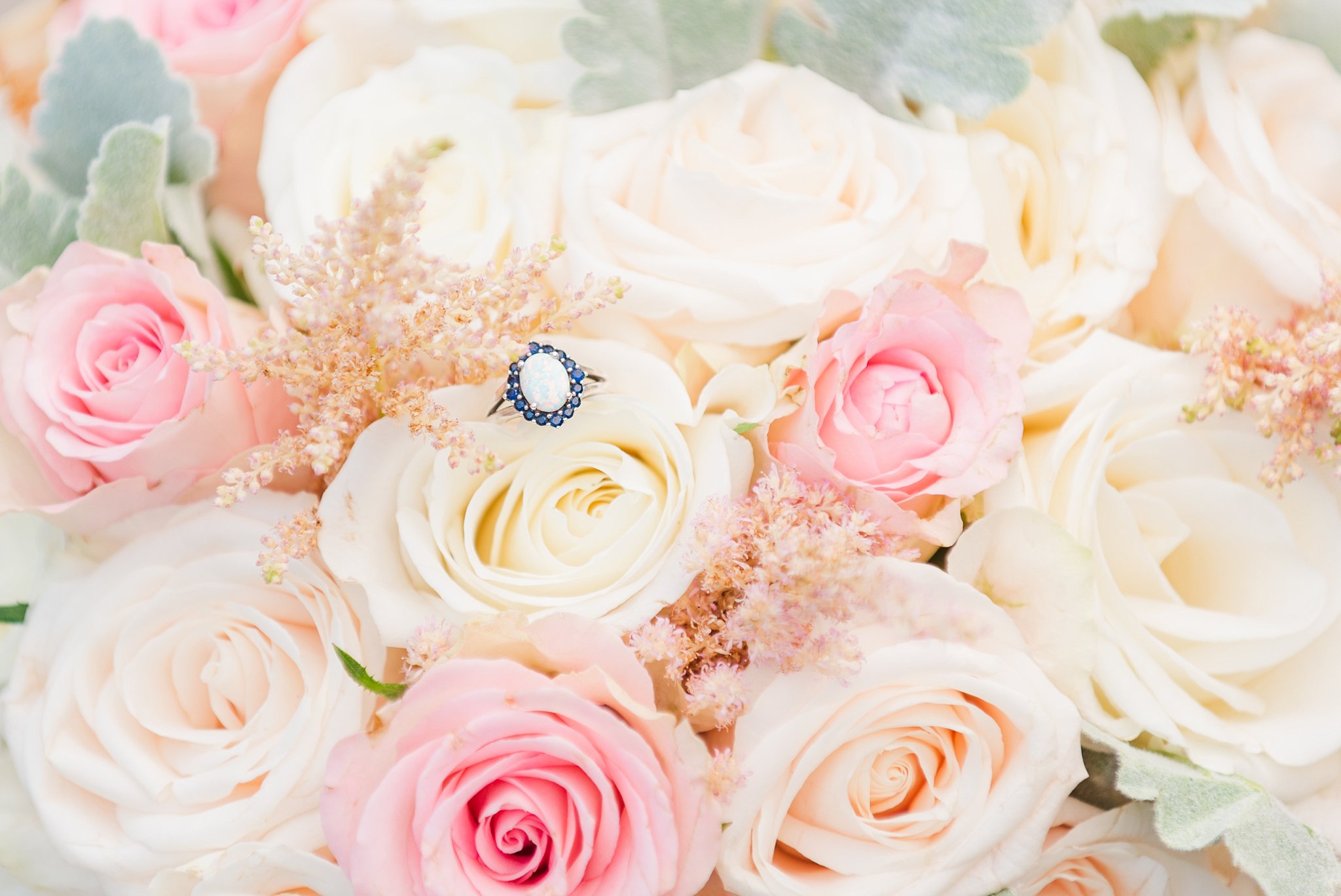 an engagement ring on a bouquet of white and pink roses