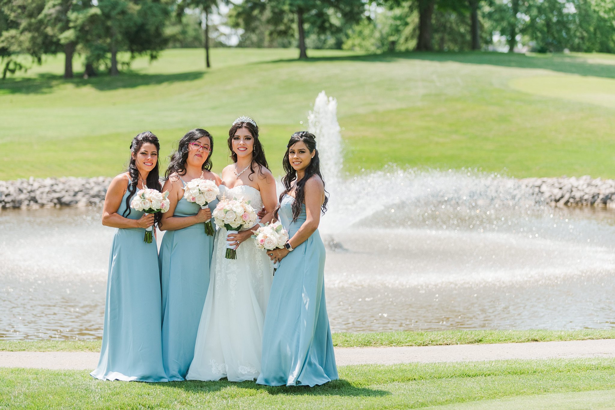 bride and bridesmaids standing in front of a fountain