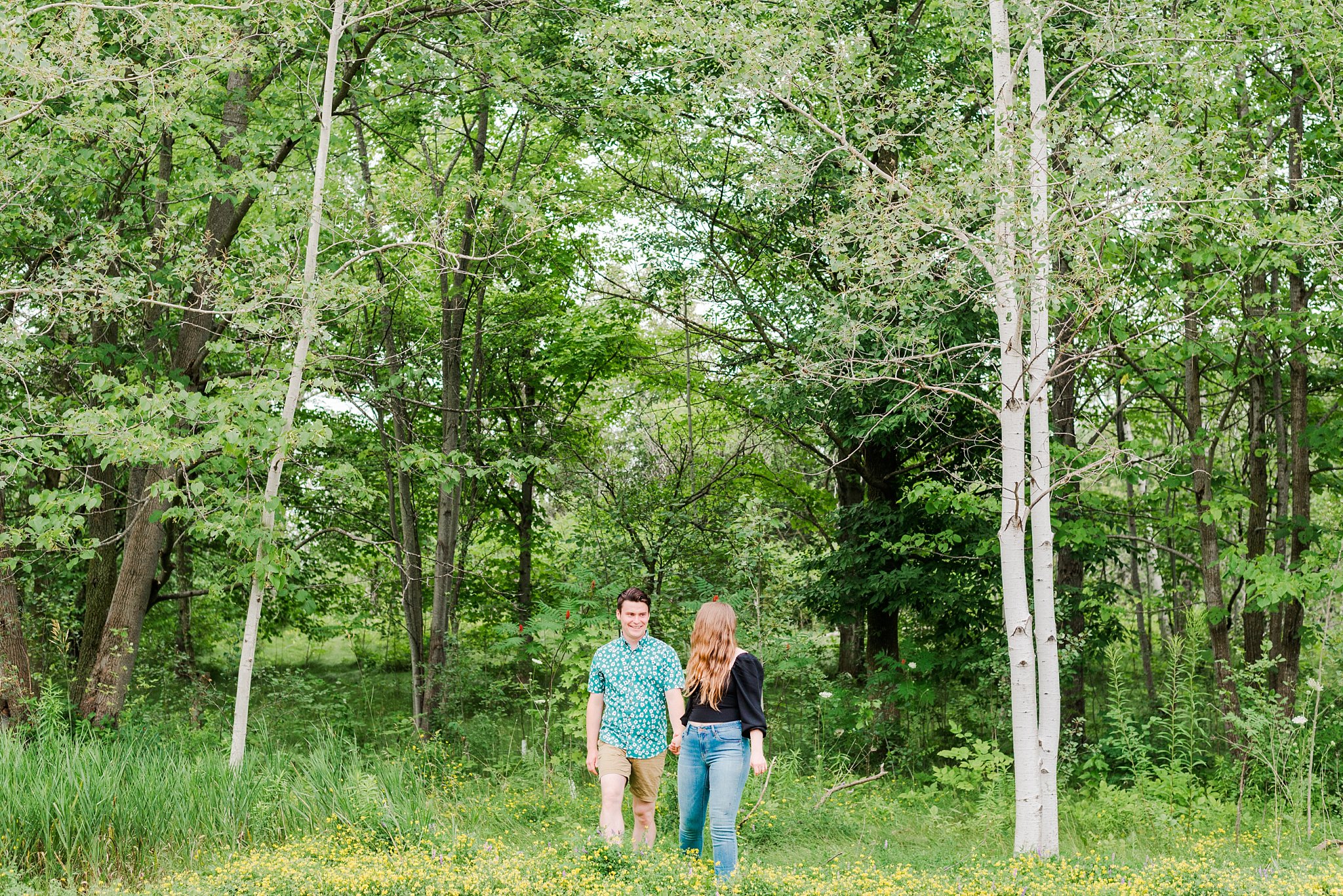a couple walks through trees together by guelph arboretum wedding photographer life is beautiful photography