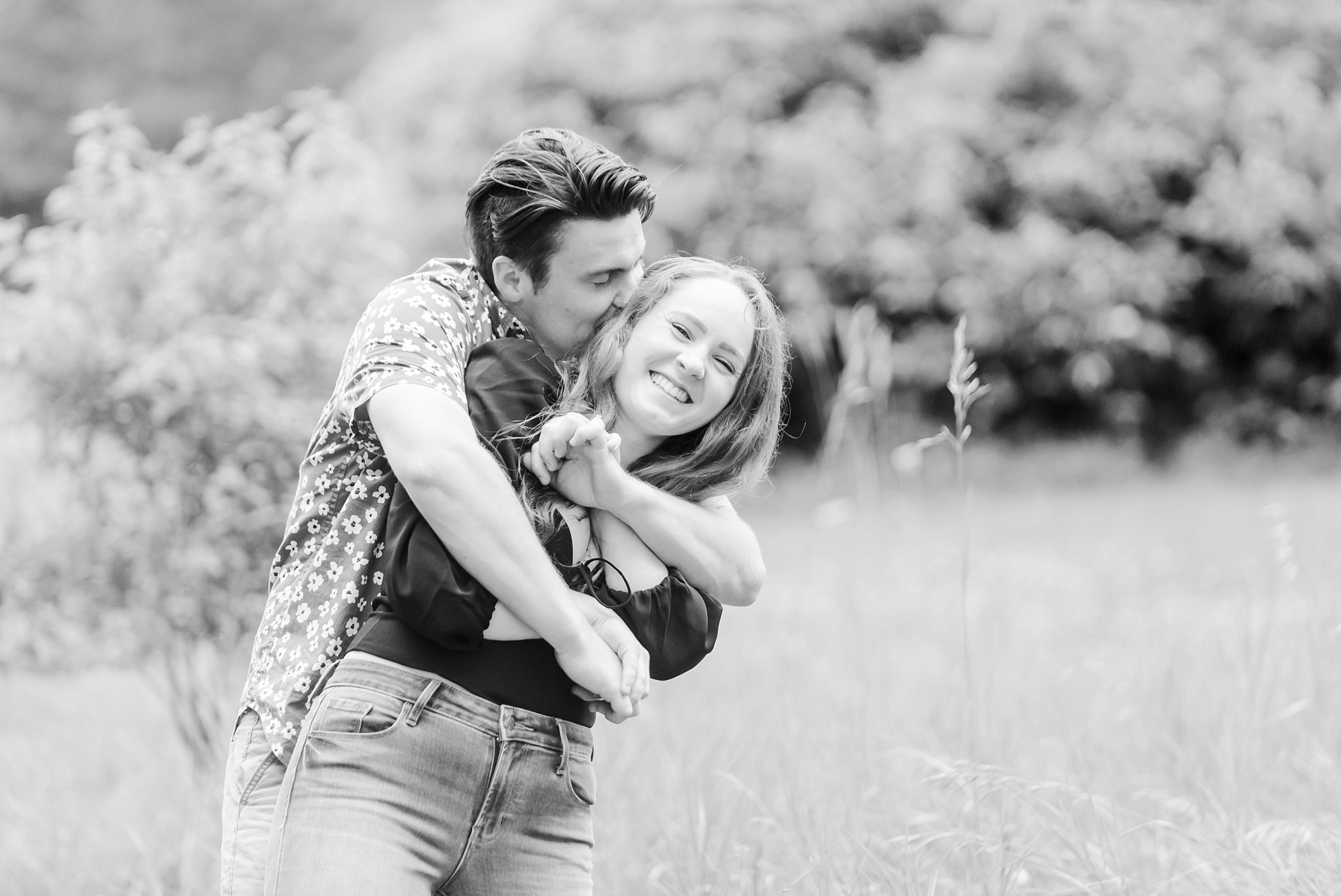 a man hugs a woman and kisses her head - black and white photo by guelph arboretum wedding photographer life is beautiful photography