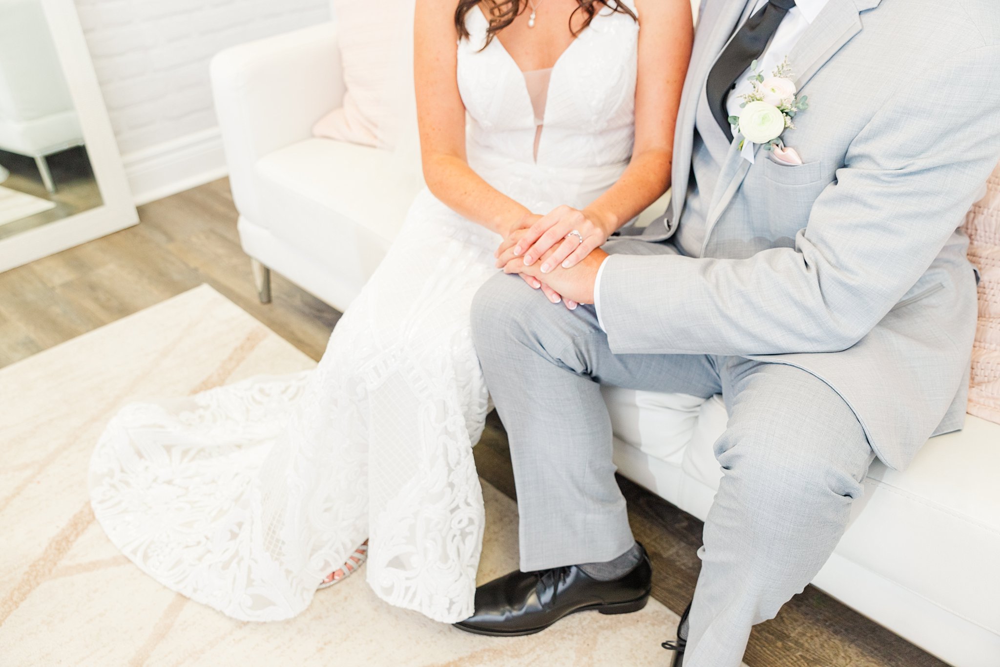 a bride and groom hold hands while sitting on a white couch at caradoc sands