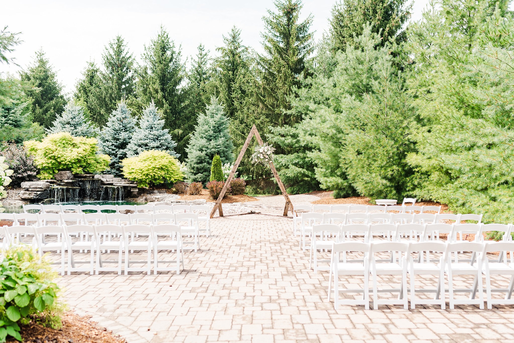 white chairs in front of a wooden triangle arbor at a caradoc sands wedding
