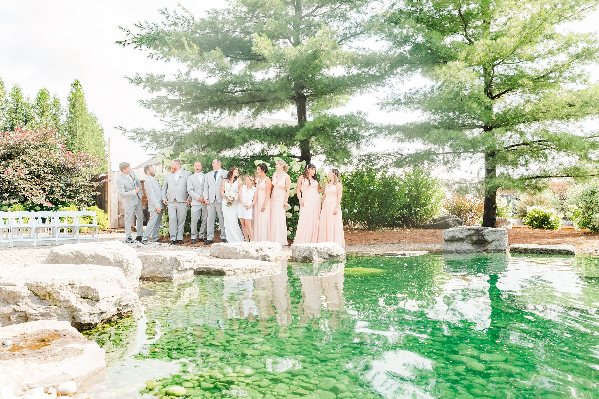 a wedding party stands across a pond at a caradoc sands wedding