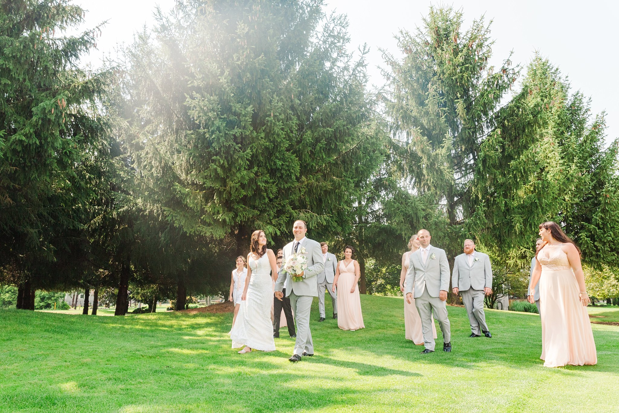 a bride and groom walk with their wedding party across grass at caradoc sands golf course
