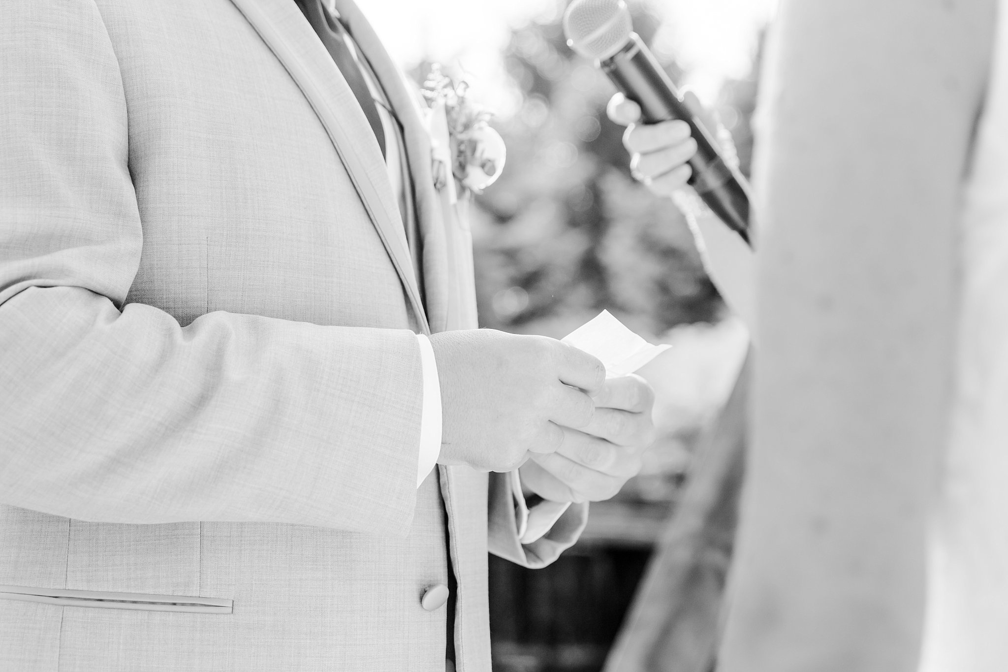 a black and white photo of a groom's hands holding his wedding vows