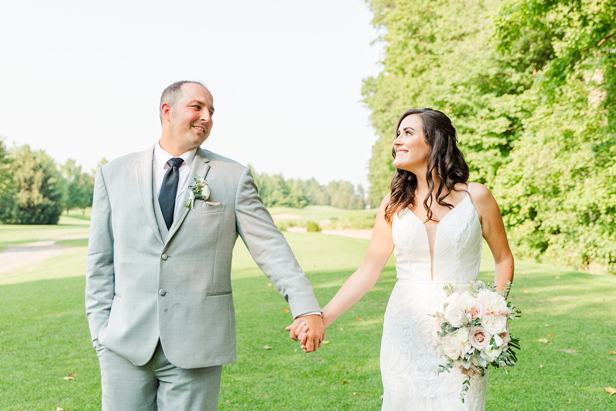 a groom and a bride are holding hands, looking at one another and smiling