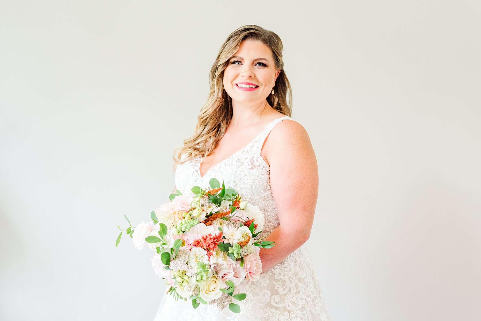 a bride holds her bouquet and smiles at the camera at fernwood hills