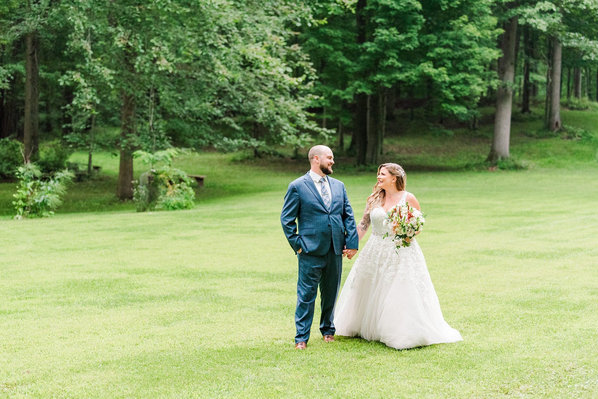 a bride and groom walk across grass at fernwood hills