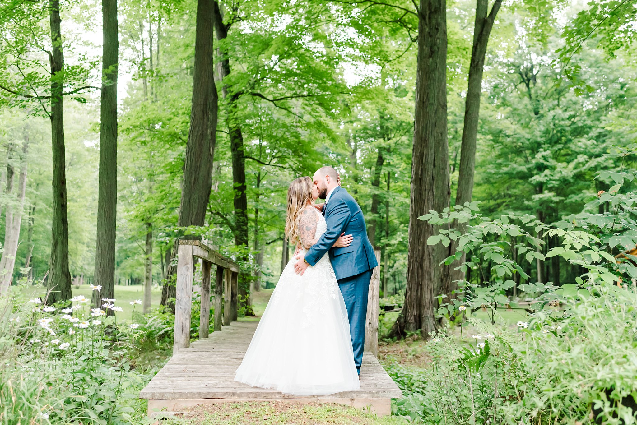 a bride and groom kiss on a wooden bridge at fernwood hills