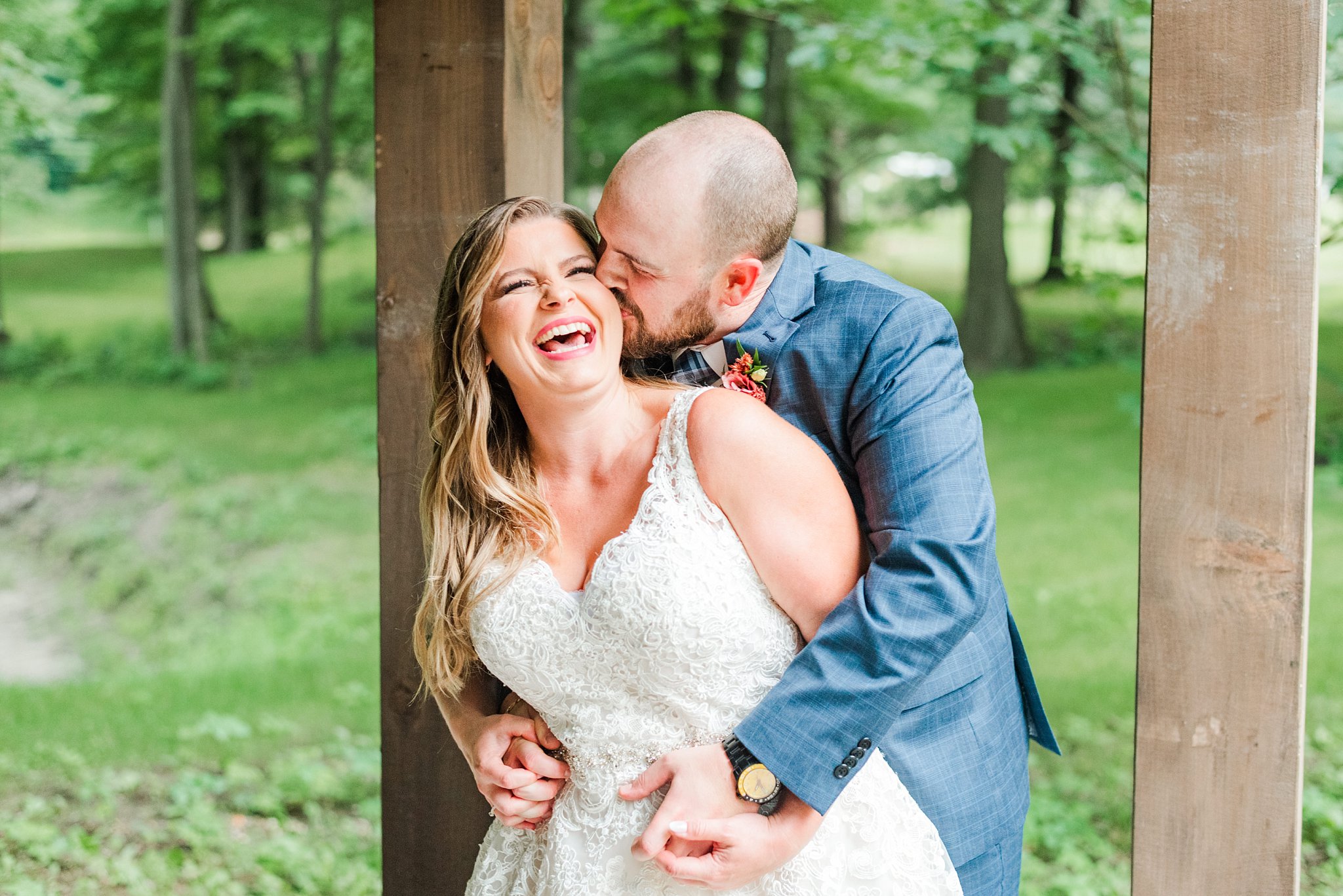 a bride laughs while the groom kisses her cheek at fernwood hills