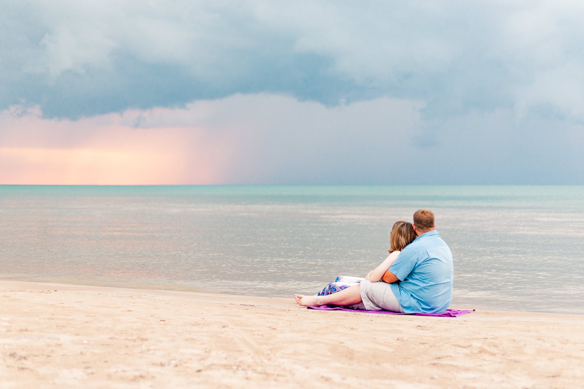 a couple watches a storm blow in during sunset in grand bend