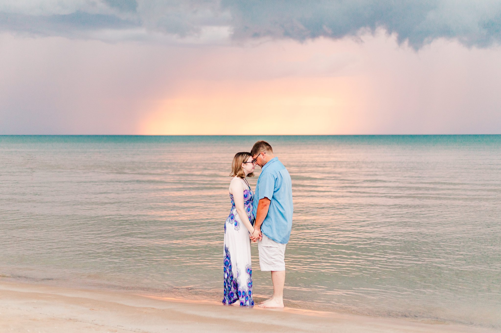 a couple leans their foreheads together with sunset and lake huron in the background. grand bend weddings