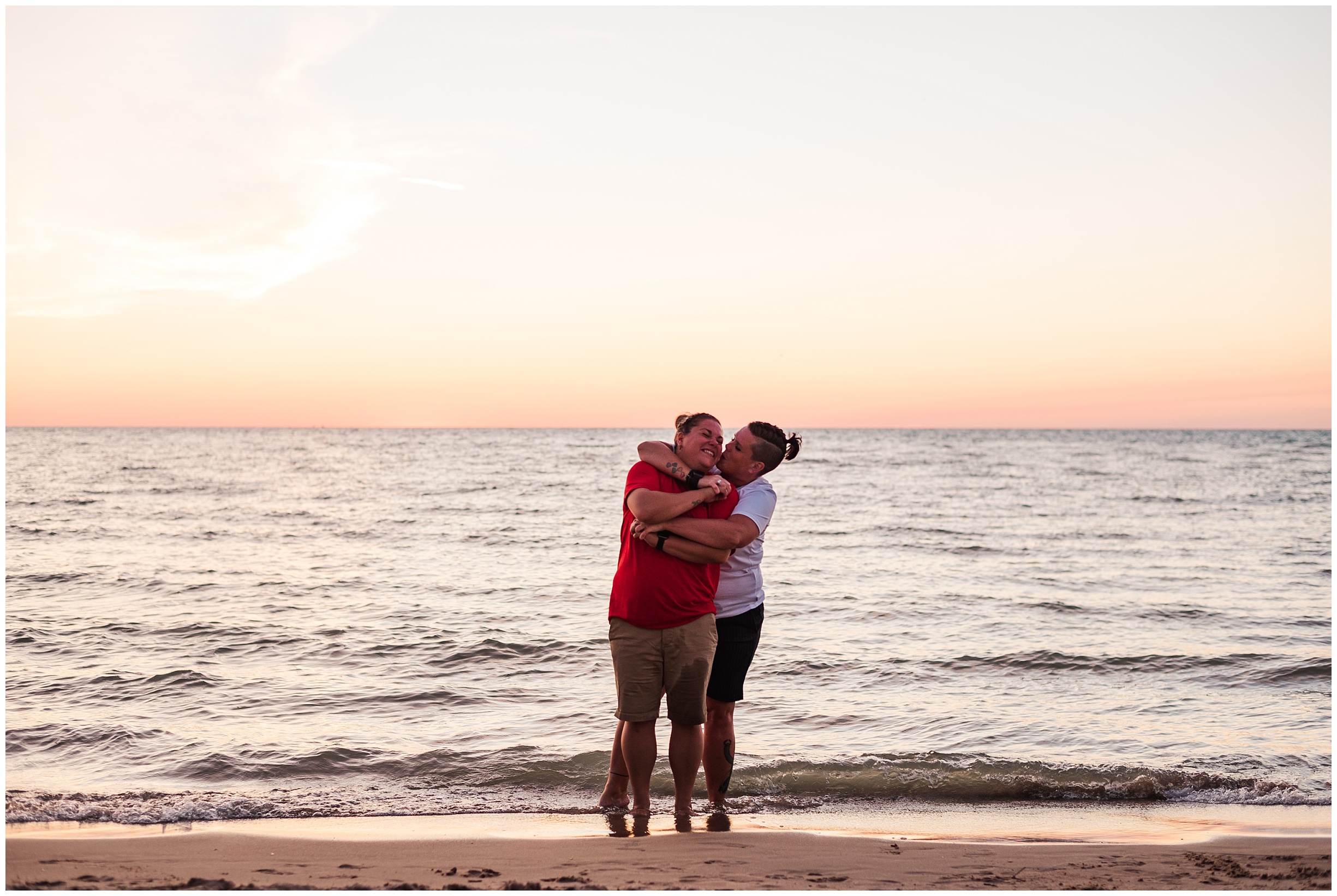 two women laugh and wrap their arms around each other while standing on the beach at sunset by toronto wedding photographer life is beautiful photography