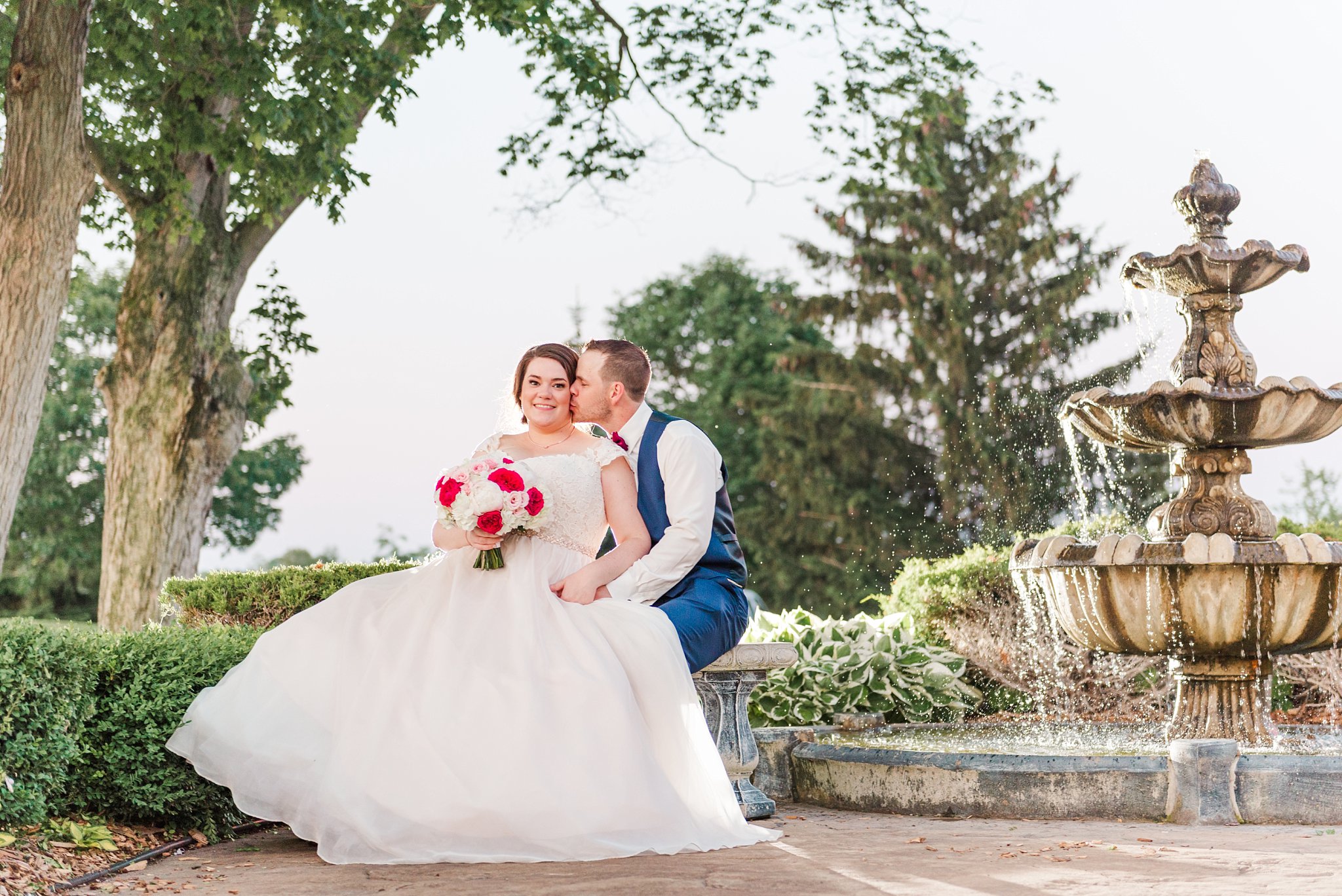 a man and woman sit on a bench beside a stone fountain. image is used in a blog post sharing business tips for wedding photographers