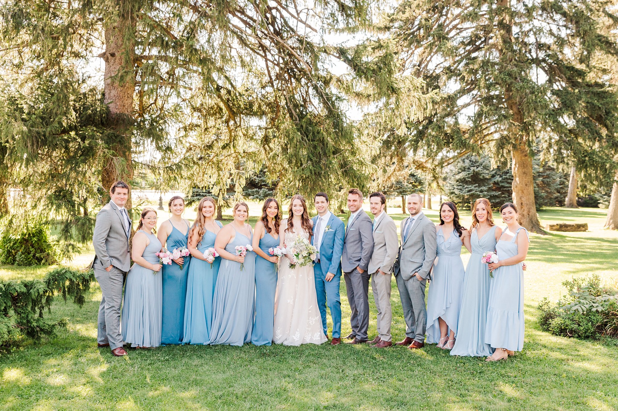 a wedding party stands in front of some trees