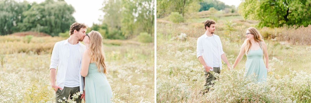 a couple walks through tall grass and white flowers while holding hands