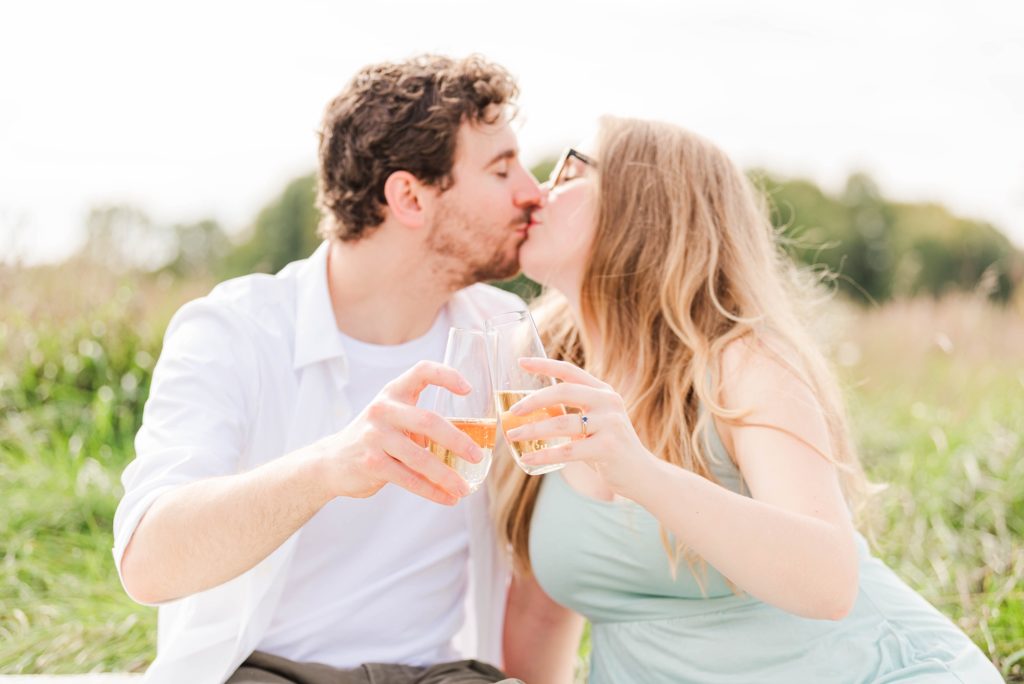 a man and woman kiss while cheersing their champagne glasses