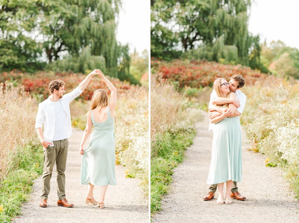 a man twirls a woman over her head while walking on a path at euston park london ontario engagement photographer
