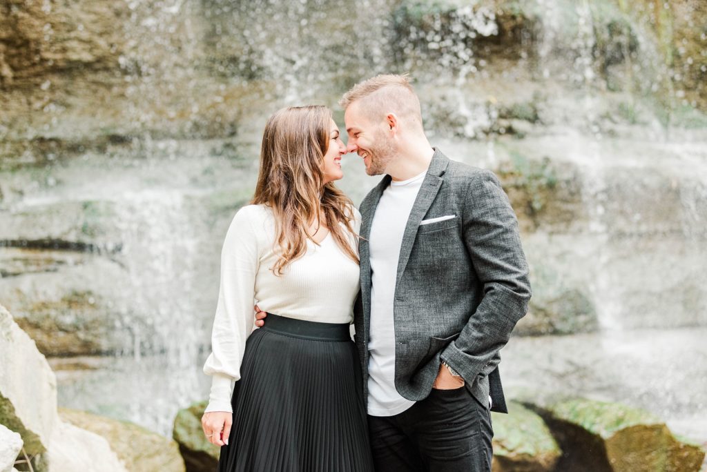 A couple nuzzles their noses together in front of the waterfall at Rock Glen Conservation Area by Kelowna Wedding Photographer Life is Beautiful Photography