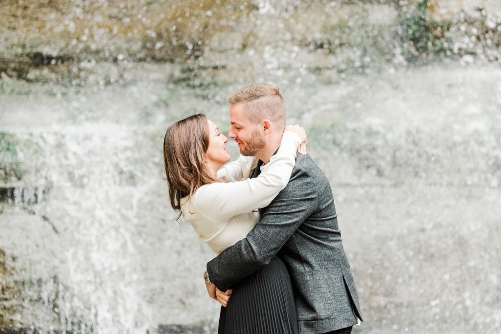 A couple hugs in front of the waterfall at Rock Glen Conservation Area by Kelowna Wedding Photographer Life is Beautiful Photography