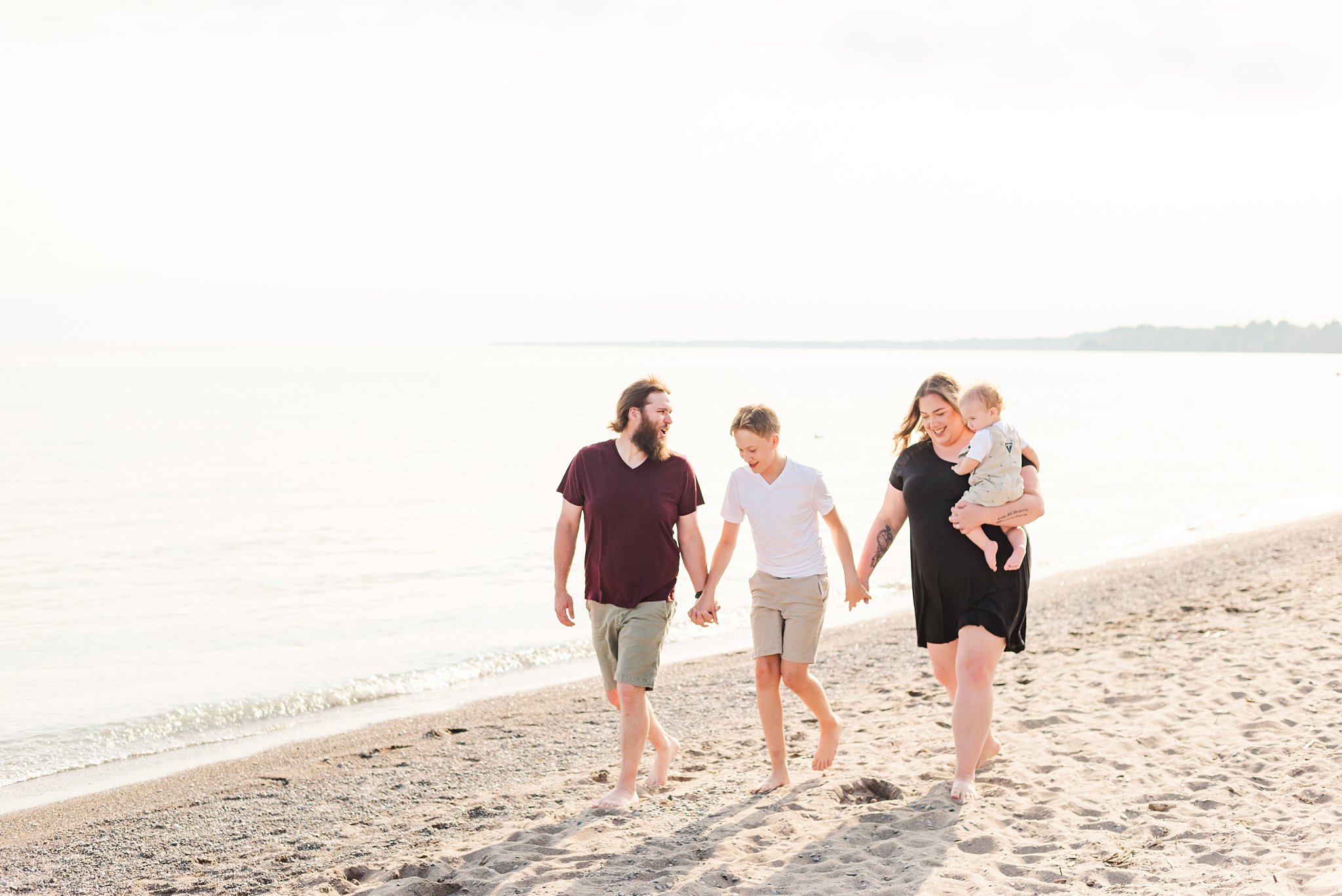 a family holds hands and walks down the beach together in port stanley